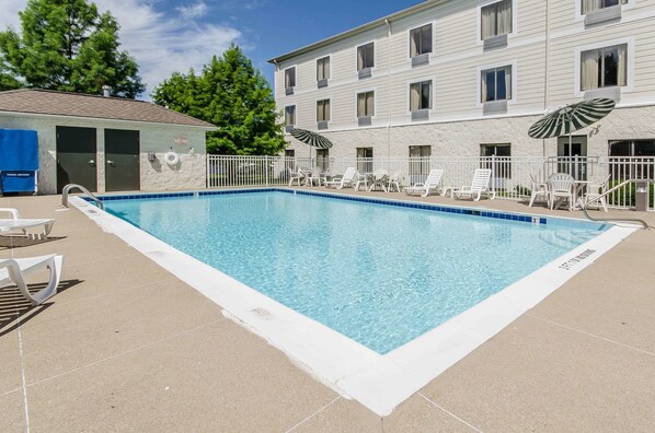 Una piscina al aire libre, sombrillas, sillones reclinables de piscina