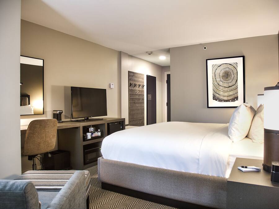 A hotel room with a large bed, a desk with a computer, a chair, and a television.