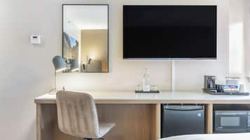 Une chambre d’hôtel équipée d’un lit, d’un bureau avec une chaise, d’un téléviseur à écran plat, d’une machine à café, d’un four à micro-ondes et d’un lave-vaisselle.