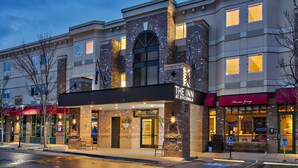 A hotel with a brick facade, a marquee sign, and a storefront with a visible entrance. - The Inn at Riverwalk (Edwards)