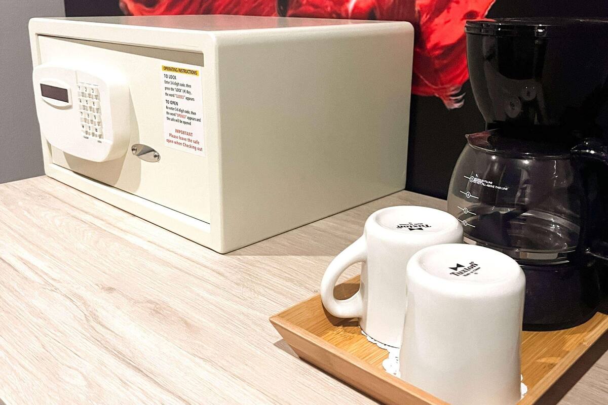 Una cafetera, dos tazas blancas y una bandeja sobre una superficie de madera.