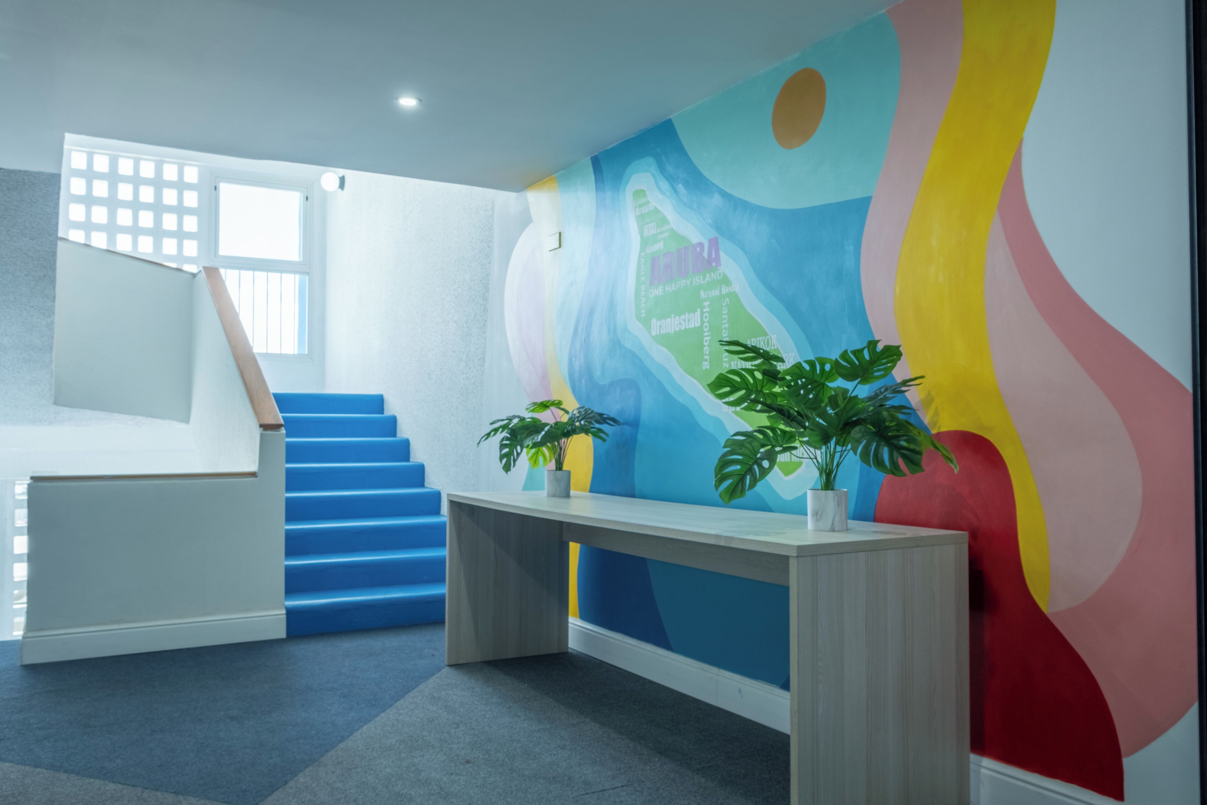 Ein modernes Interieur mit Treppe, Schreibtisch und einem farbenfrohen, abstrakten Wandbild.