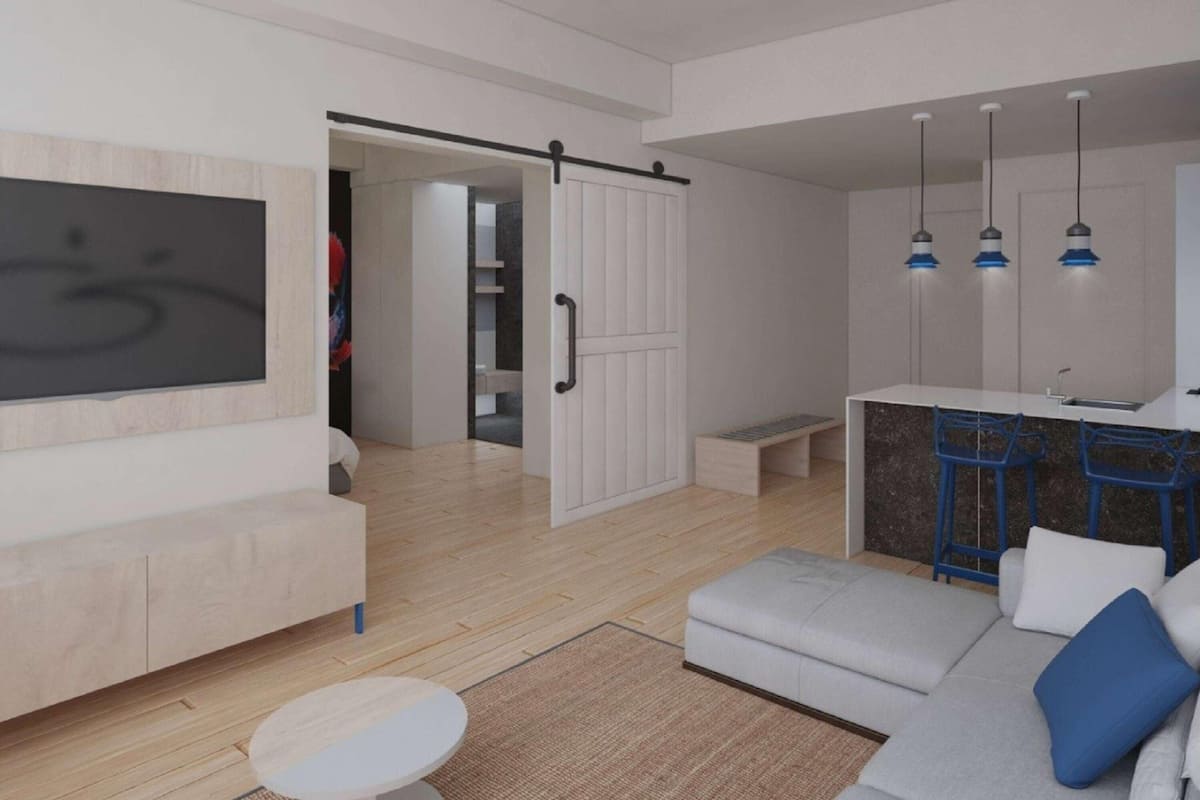 Una sala de estar moderna con un sofá, un reposapiés y un televisor montado en la pared.