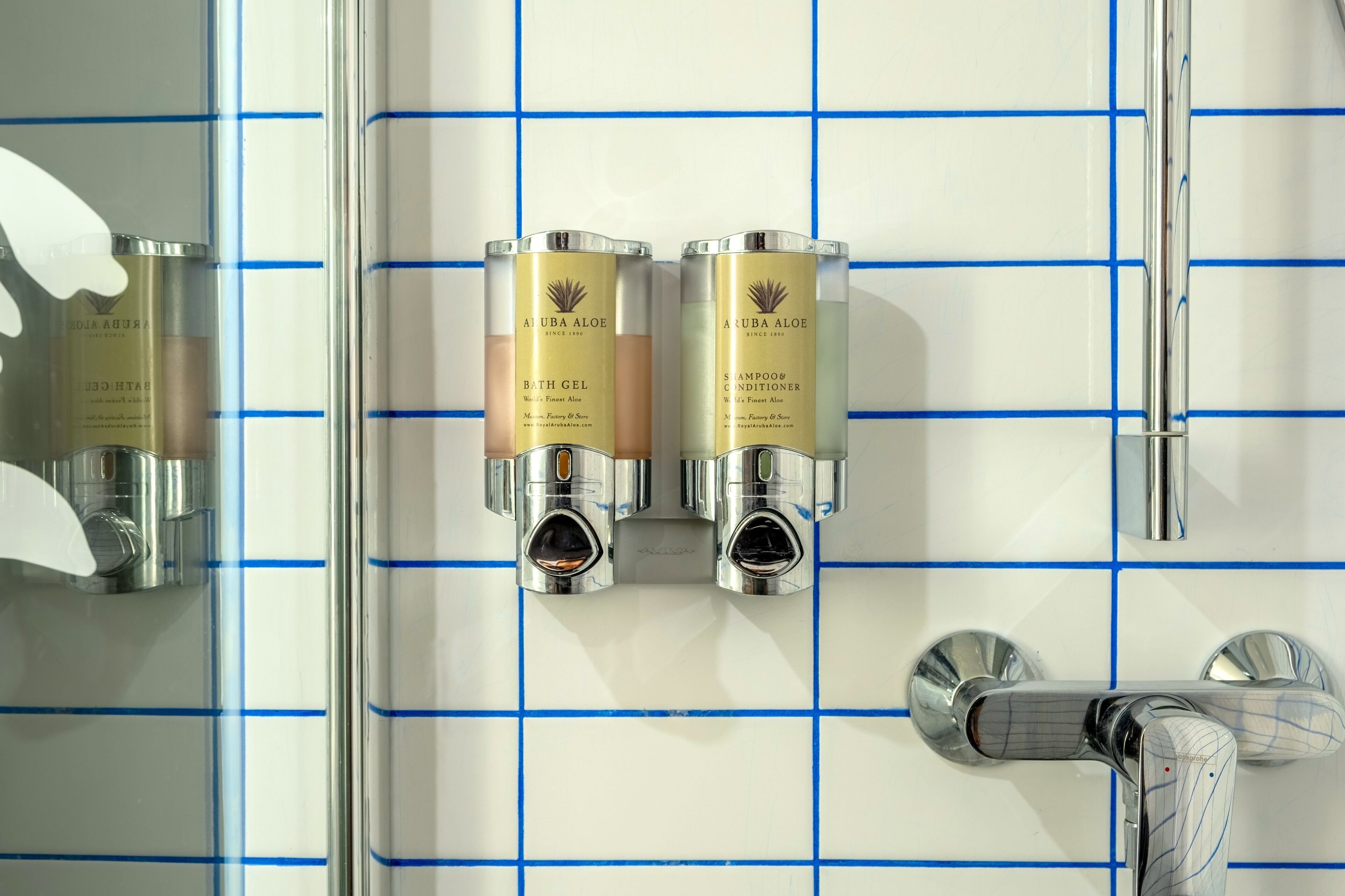 Une salle de bain équipée de deux distributeurs de gel douche à base d’aloe vera d’Aruba et d’un robinet chromé.