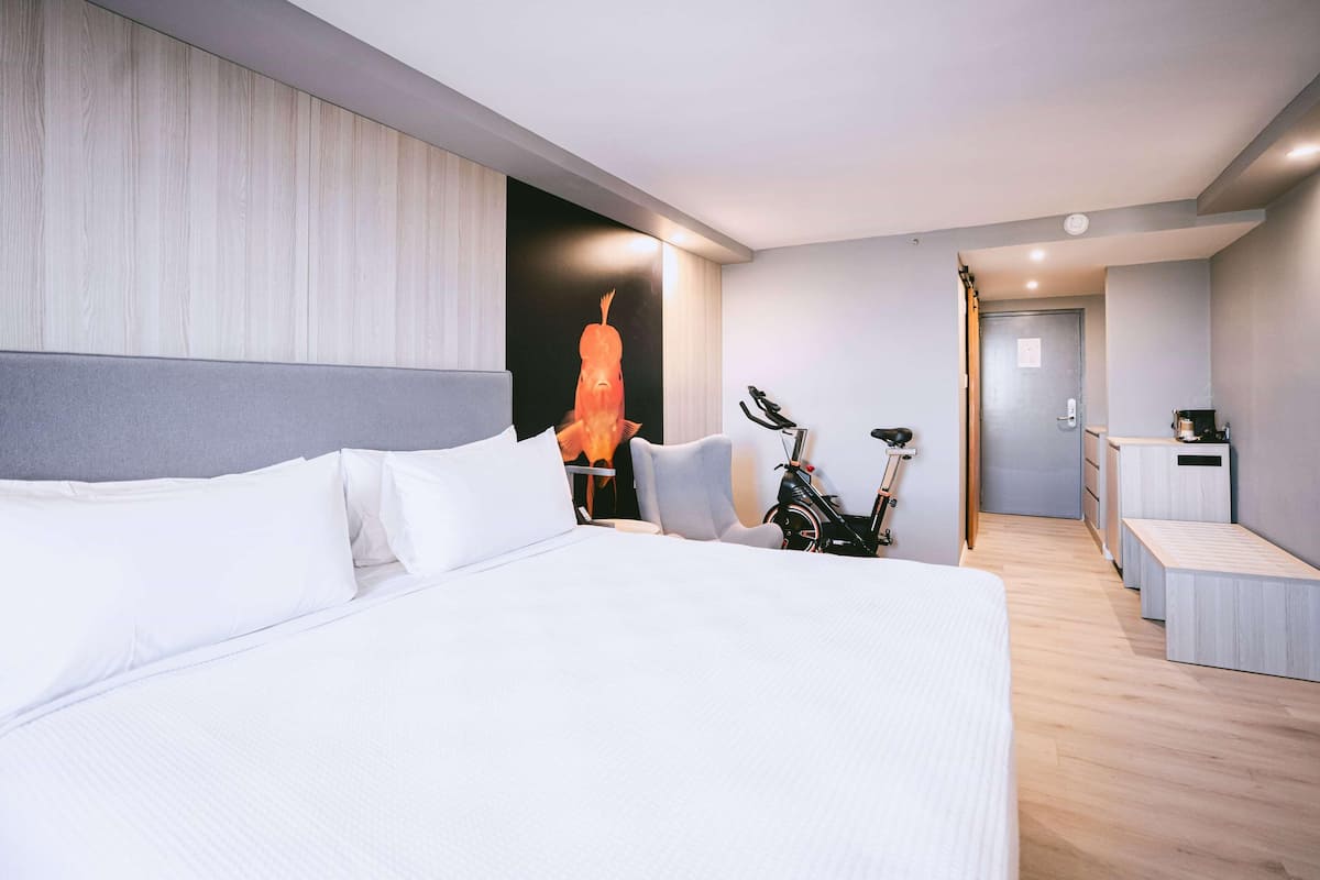 Una habitación de hotel moderna con una cama grande, una bicicleta y una kitchenette.