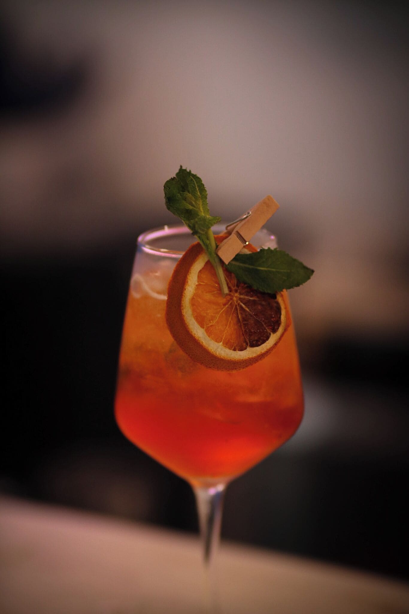 Un vaso de cóctel con una rodaja de naranja y una hoja de menta.