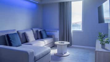 Una sala de estar moderna con un sofá gris, una mesa de centro redonda, un televisor de pantalla plana y una planta en maceta.