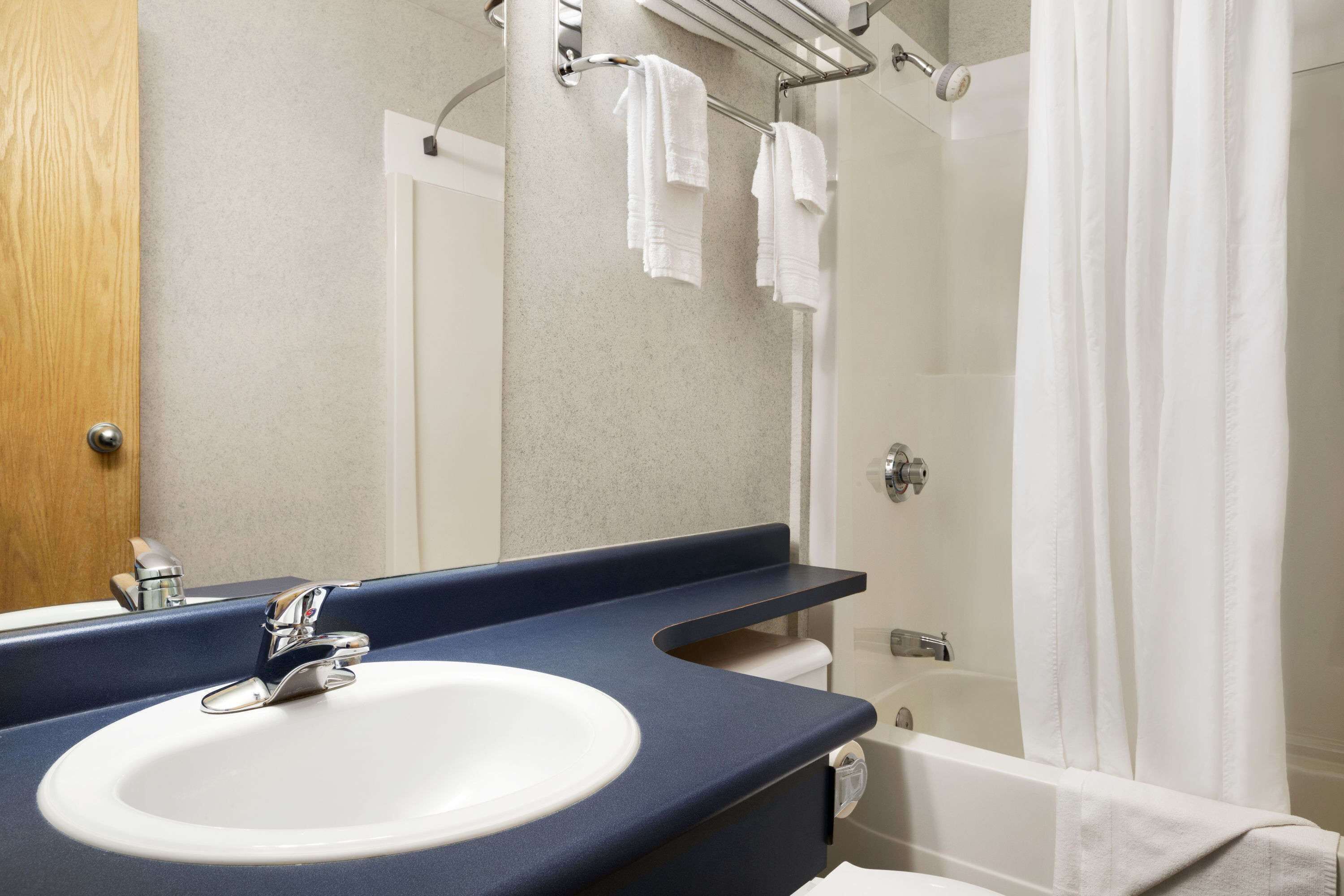 A bathroom with a sink, mirror, and bathtub.