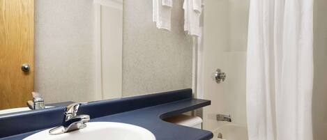 A bathroom with a sink, mirror, and bathtub.