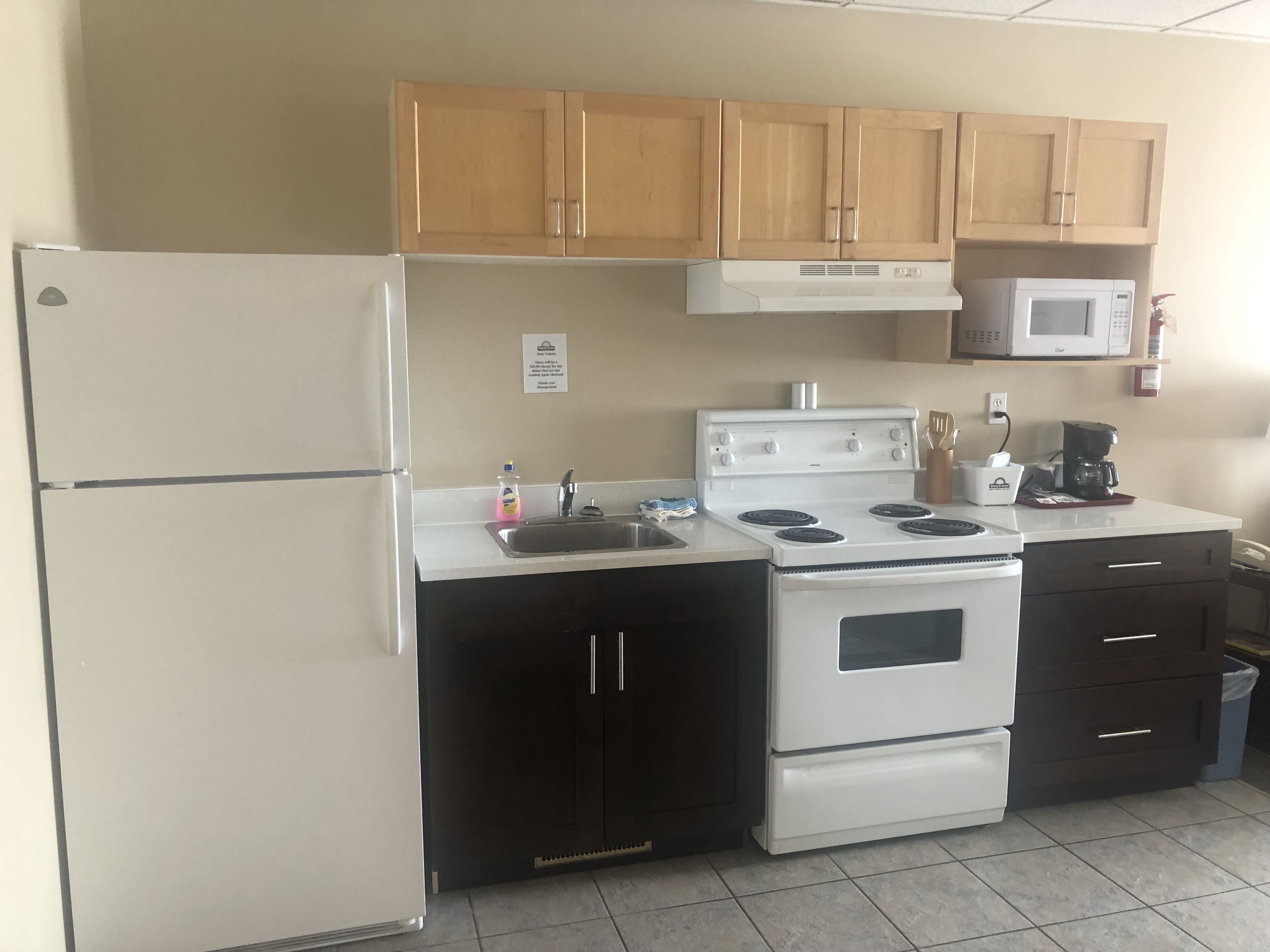 A compact kitchen with a refrigerator, stove, microwave, and dark cabinets.