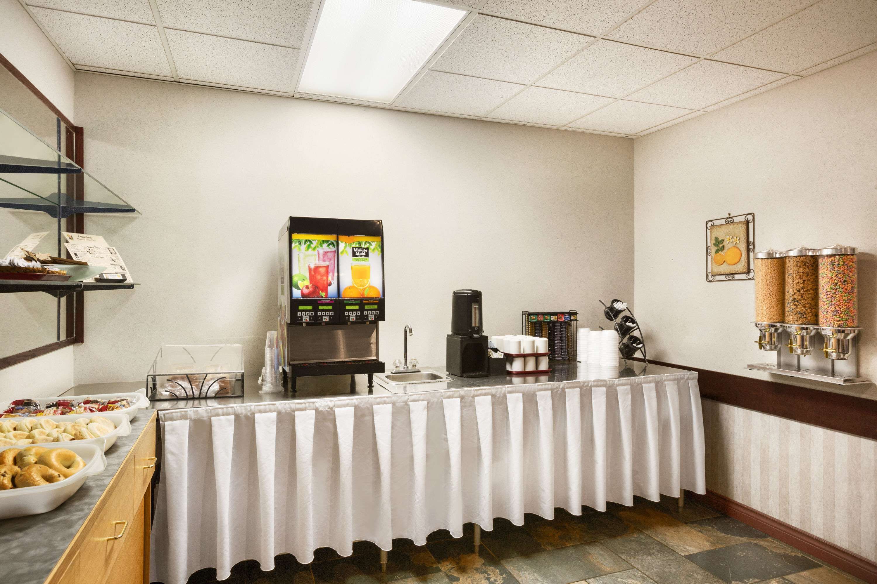 A buffet area with a self-serve beverage station, a coffee machine, and a variety of food items on display.