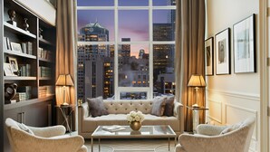 Una sala de estar moderna con vistas a la ciudad, un sofá, dos sillones, una mesita de centro y una estantería.