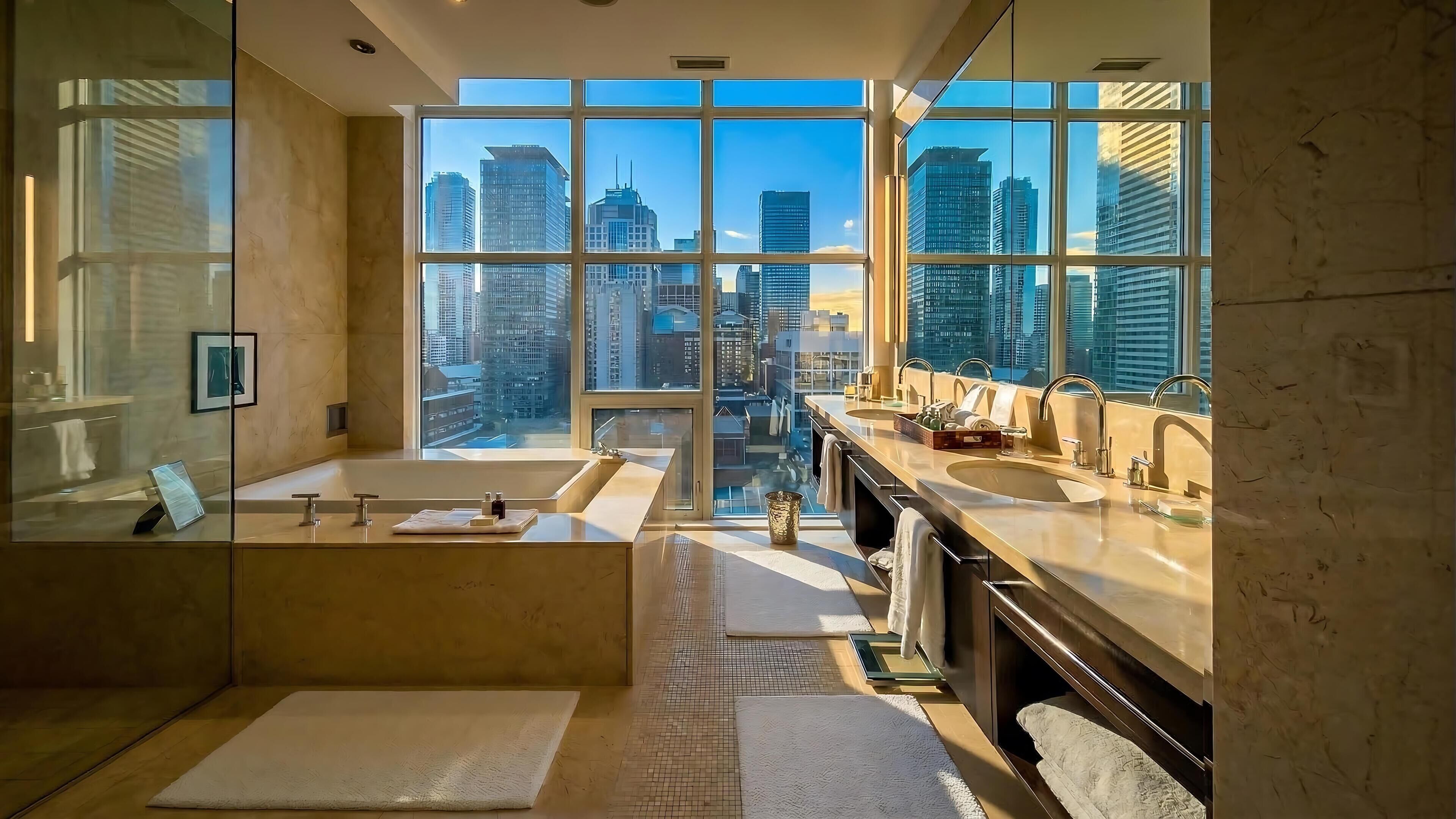 A modern bathroom with a large window, a bathtub, and a vanity with multiple sinks.