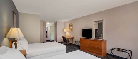 A hotel room with two beds, a desk with a chair, a dresser, a television, and a mirror.