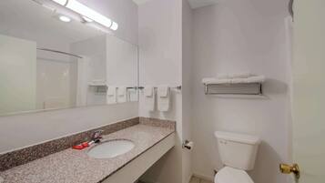 A bathroom with a sink, mirror, toilet, and towel rack.