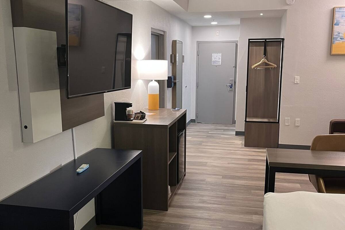 Een hotelkamer met een bureau, een bed, een televisie, een lamp, een kast en een deur.