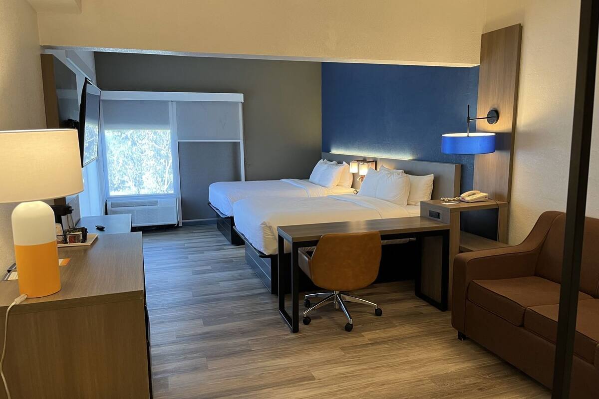 Een hotelkamer met een bed, bureau, stoel en een bank.