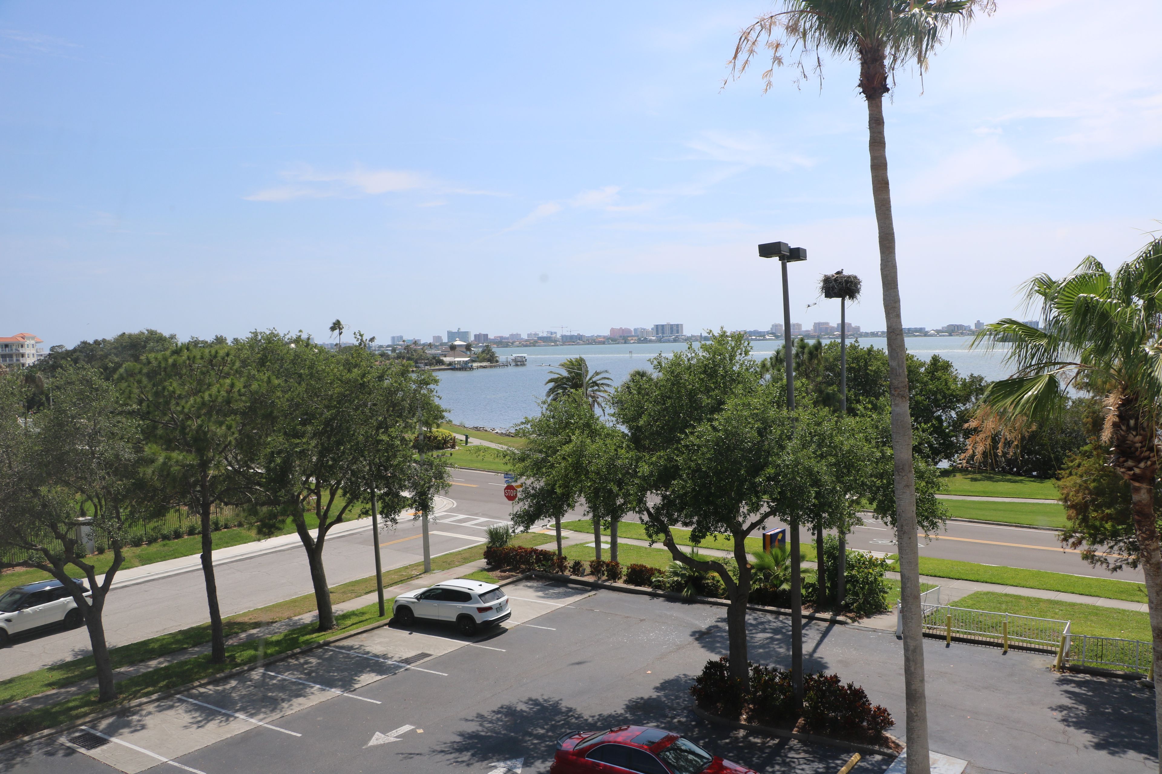 Un área de estacionamiento con vistas a un cuerpo de agua y un horizonte urbano a lo lejos.