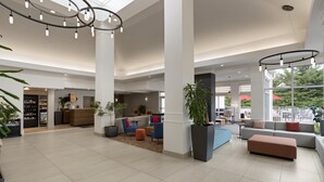 Eine geräumige Lobby mit einer Rezeption, Sitzbereichen und großen Fenstern.