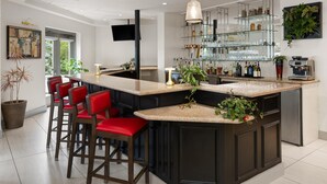 Eine moderne Küche mit einer zentralen Kochinsel, einer Bar mit Glastregalen und roten Barhocker.
