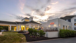 Ein Hotel mit modernem Design, das eine großzügige Eingangshalle mit überdachtem Bereich und einem sichtbaren Garten bietet.