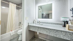 A bathroom with a granite countertop, a white sink, a mirror, and a shower curtain. - Econo Lodge Russellville (Russellville)