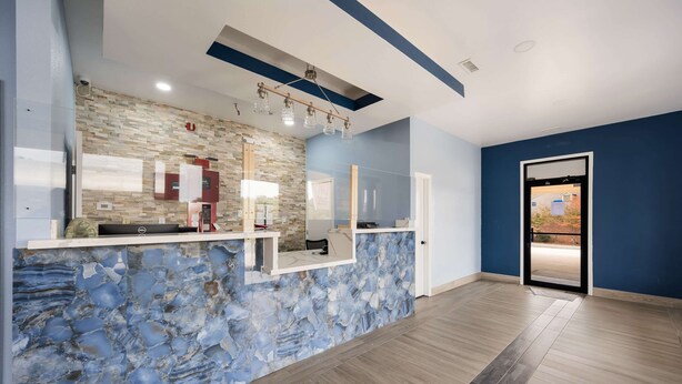 A reception area with a stone wall, a reception desk, and a door leading outside. - Econo Lodge Russellville (Russellville)
