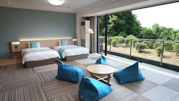 A hotel room with two beds, a balcony with a view, and a small table with chairs.