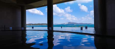 An indoor swimming pool with a view of the ocean and mountains.