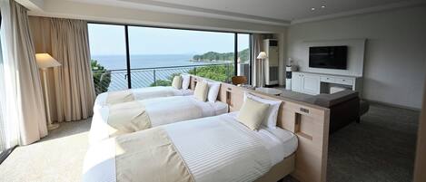 Ein Hotelzimmer mit zwei Betten, einem Fernseher und einem Balkon mit Meerblick.