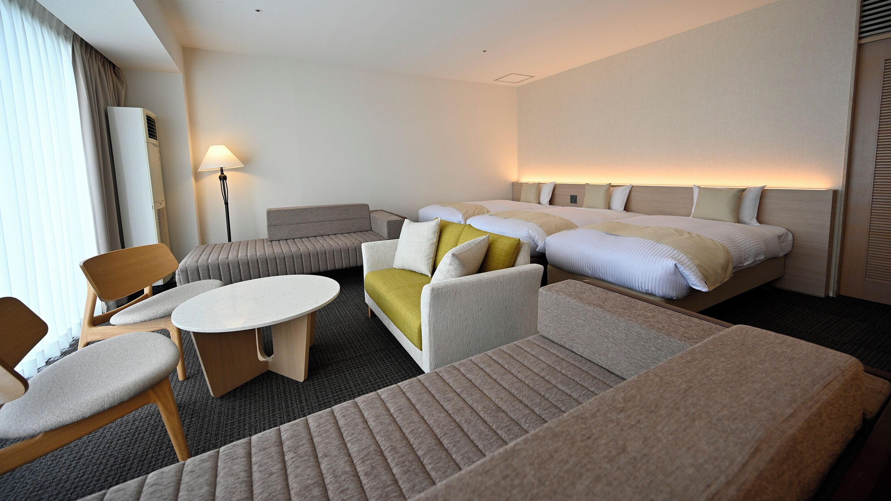 Habitación de hotel con cama, sofá, sillón y una mesita.
