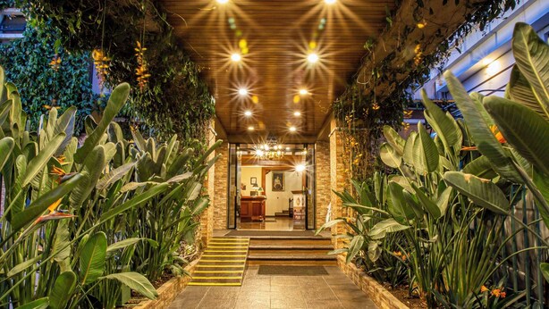A well-lit pathway leading to a reception area with a wooden ceiling and lush plant walls.