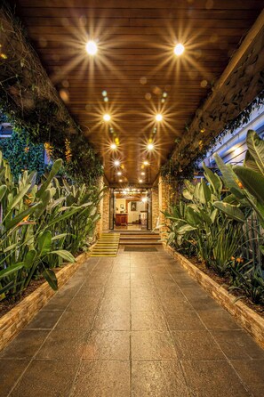 A well-lit pathway leading to a reception area with a wooden ceiling and lush plant walls.