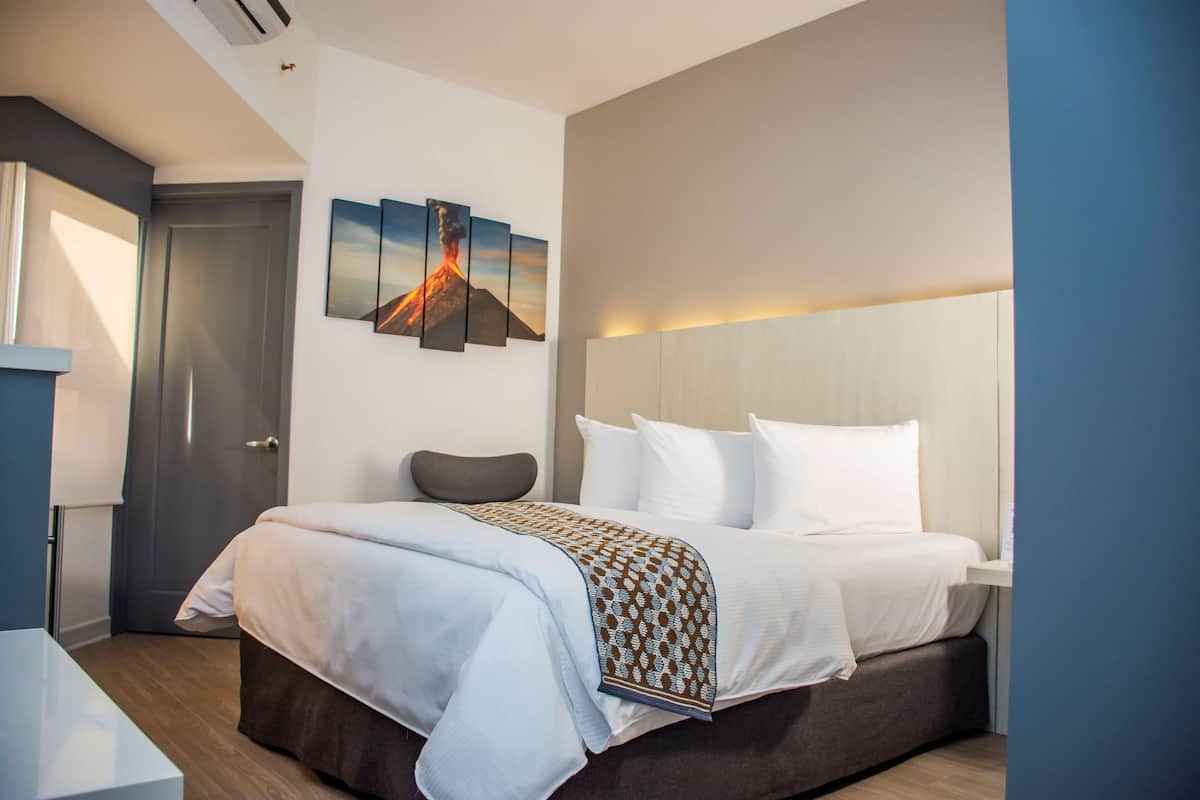 Een moderne hotelkamer met een groot bed, een nachtkastje, een wanddecoratie van een vulkaan.
