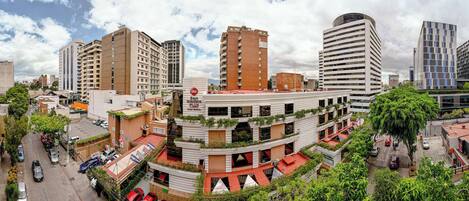 A multi-story building with a modern design, featuring balconies and a rooftop garden.