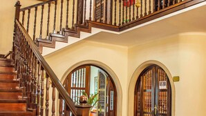 A grand staircase with a chandelier, wooden railings, and a polished wooden floor.