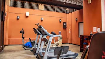 Un gimnasio con cintas de correr, bicicletas estáticas y una máquina de remo.