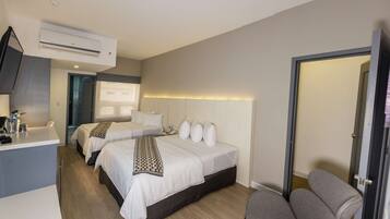 A hotel room with two beds, a desk with a flat-screen TV, a coffee maker, and a minibar.
