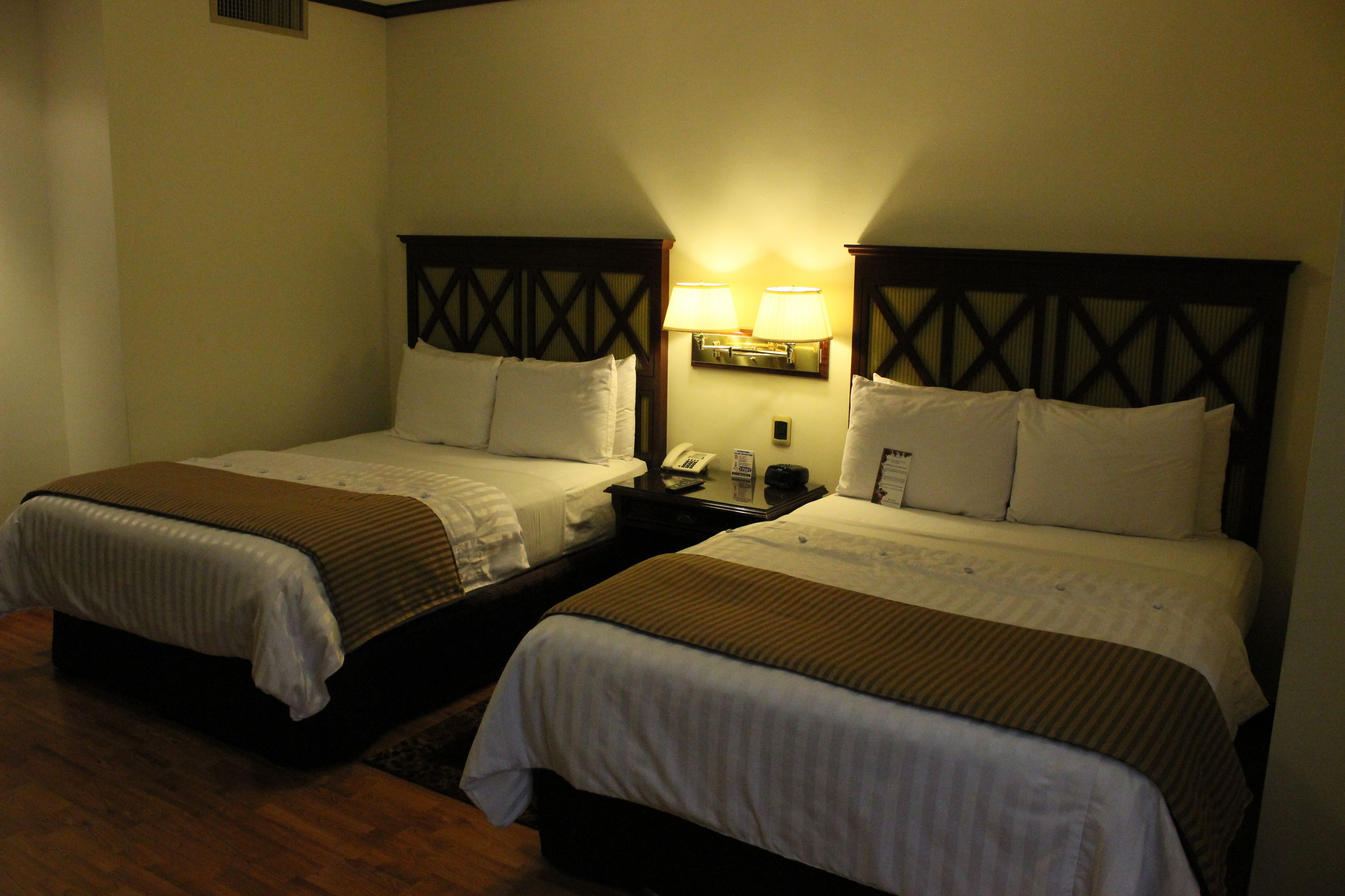 Two adjacent beds with headboards, bedside lamps, and a telephone on the nightstand.