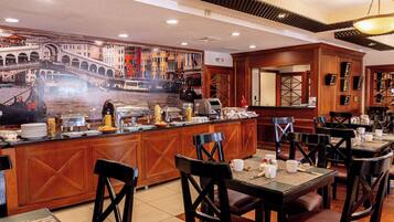 A restaurant with a buffet counter, wooden furniture, and a mural of a bridge.