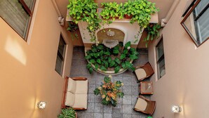 A courtyard with a central seating area, surrounded by potted plants and a decorative fountain.
