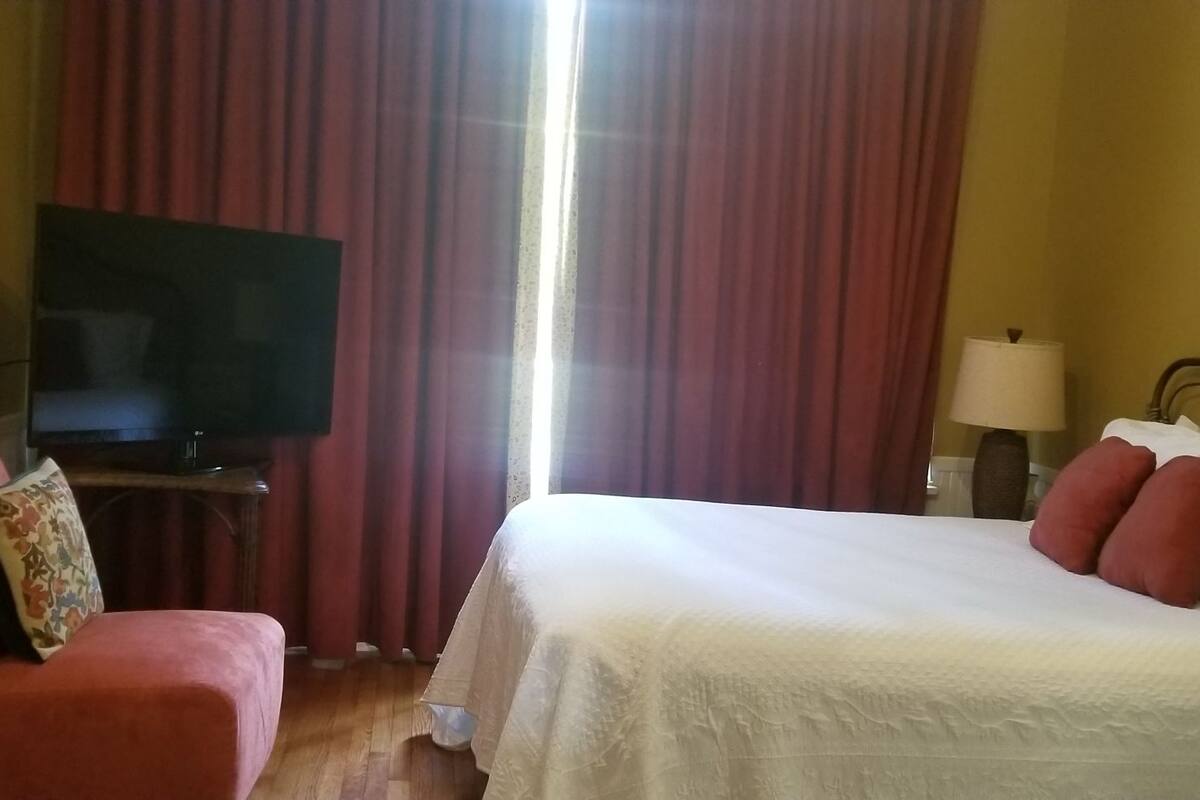 A hotel room with a bed, a television, a chair, and a lamp.