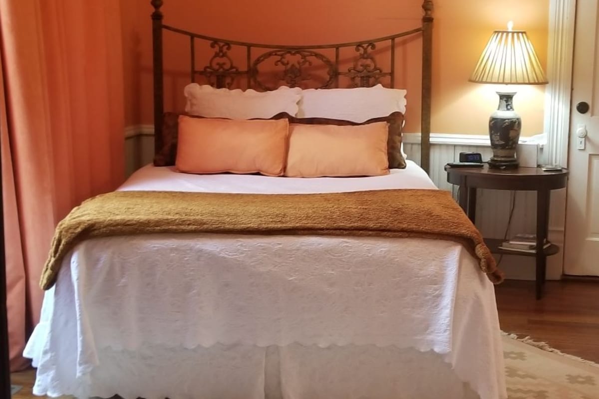 A bedroom with a bed, a nightstand, a lamp, and a patterned rug.