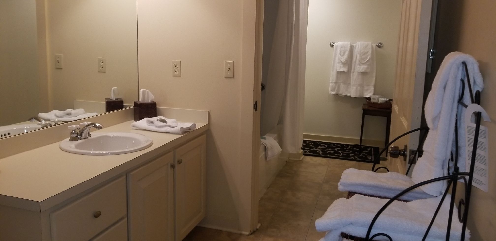 Un baño con lavamanos, espejo y toallero.