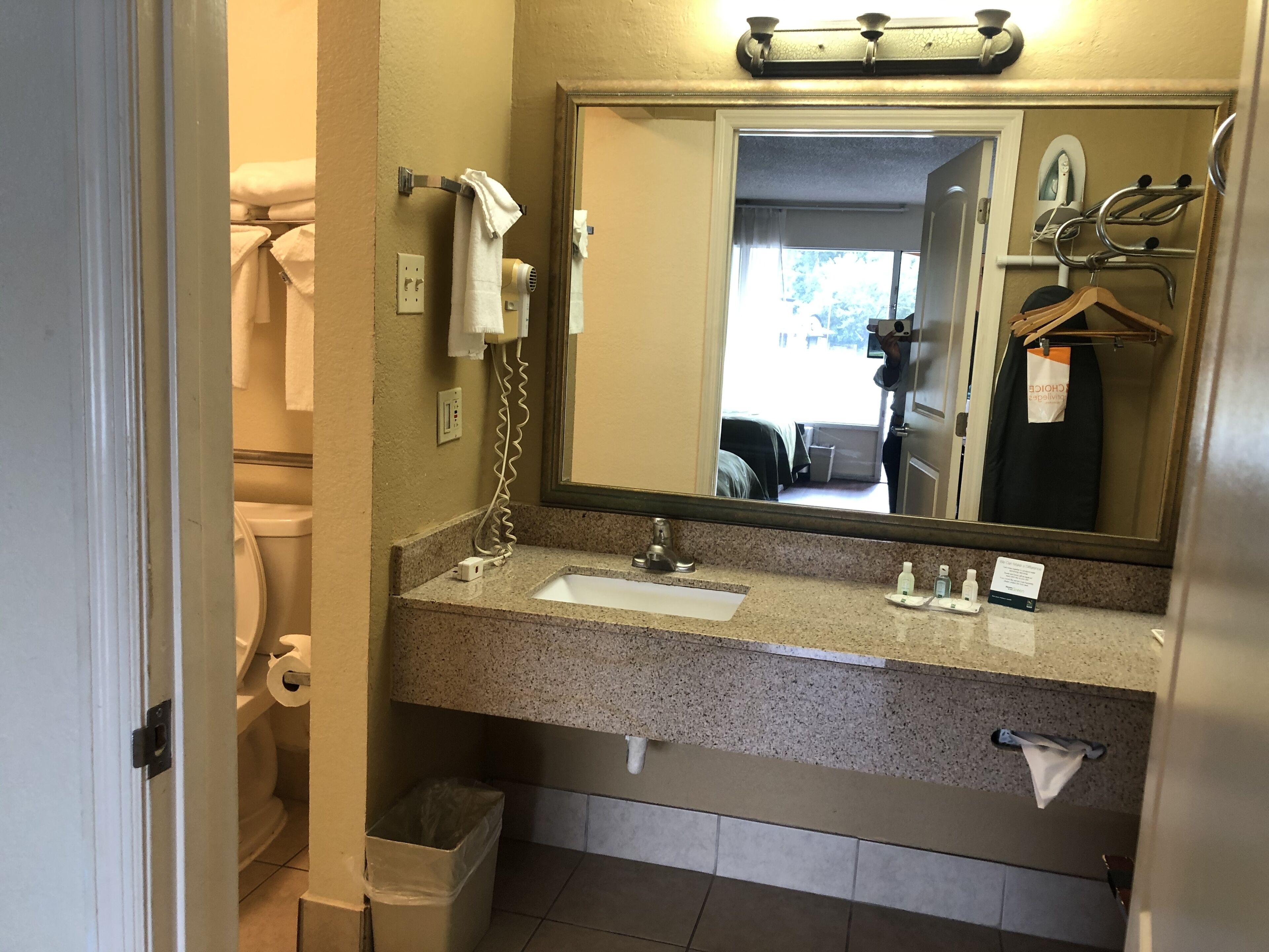 Un baño con lavamanos, espejo, toallero y cubo de basura.