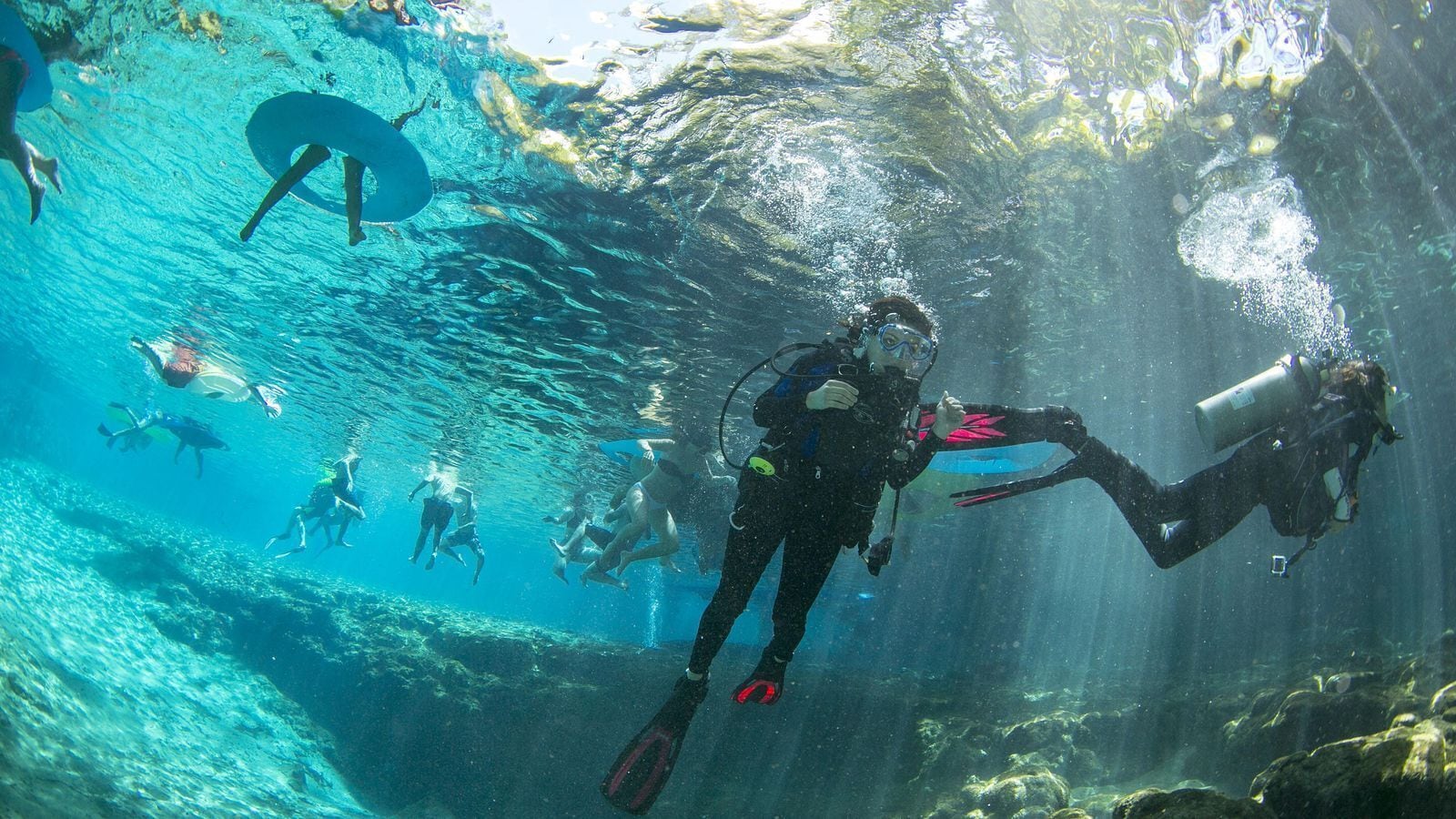 An underwater scene with divers exploring a clear blue aquatic environment.