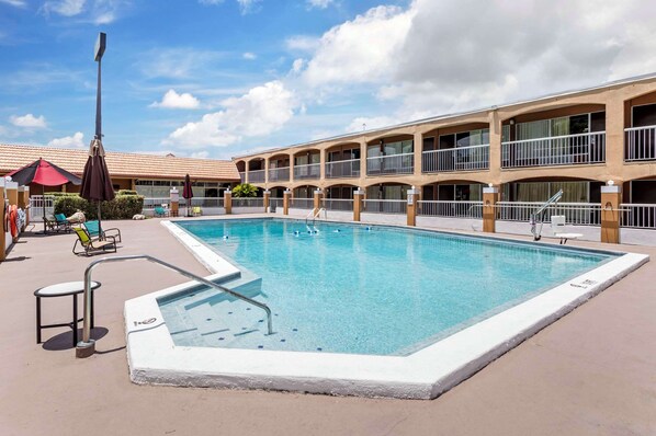 Relax by the pool surrounded by lounge chairs and umbrellas, with access via a metal ladder.