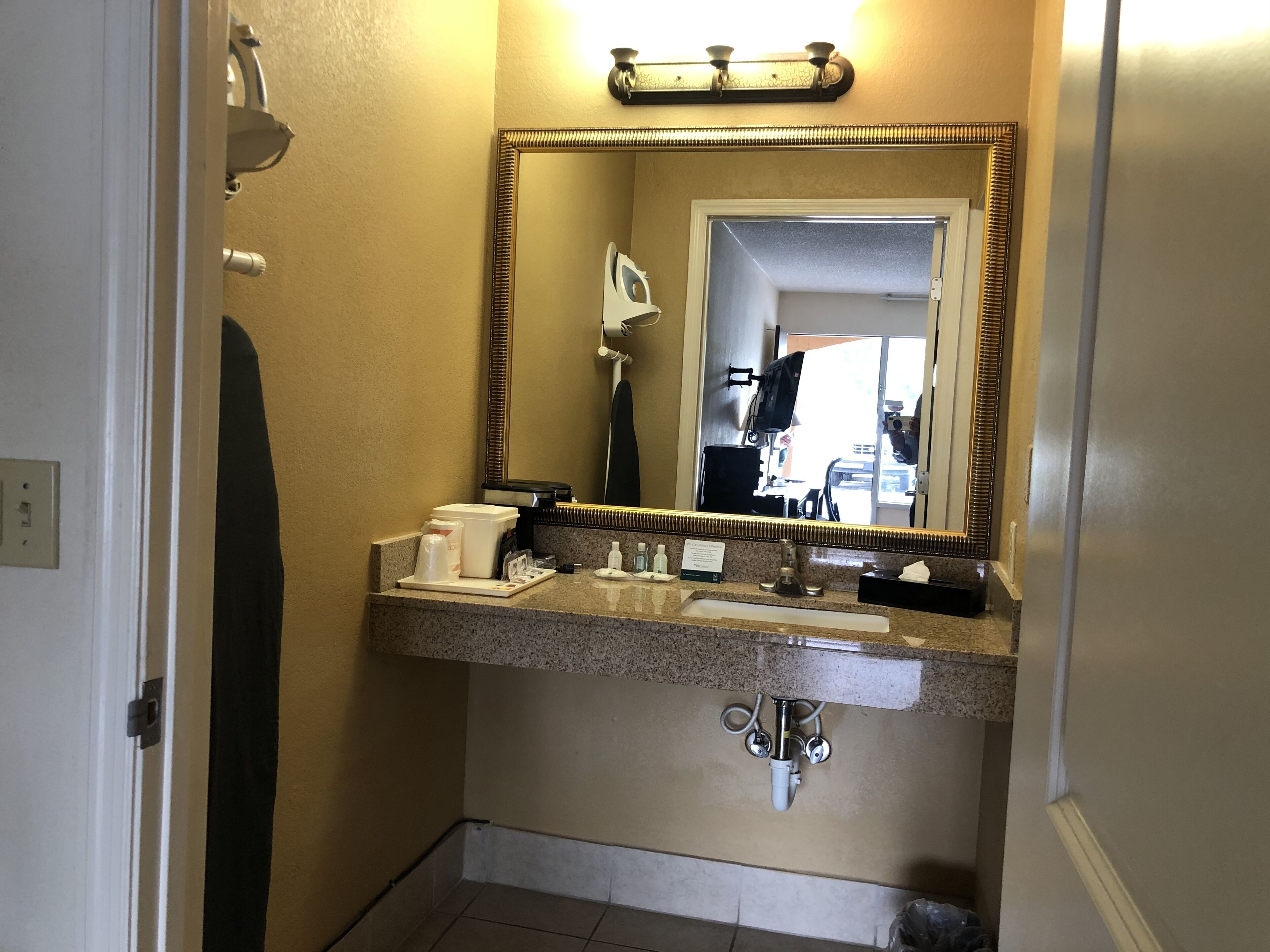 Un baño con encimera de granito, un lavabo, un espejo y un perchero para toallas.