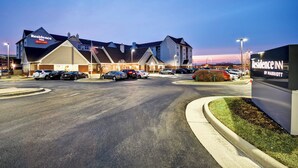 Um hotel com design moderno, vários espaços de estacionamento e entrada bem iluminada.