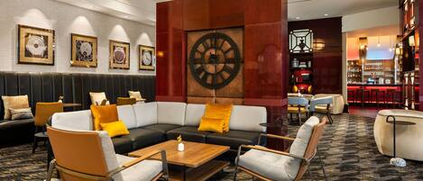 A modern lounge area with a sectional sofa, armchairs, a coffee table, and a large wall clock.